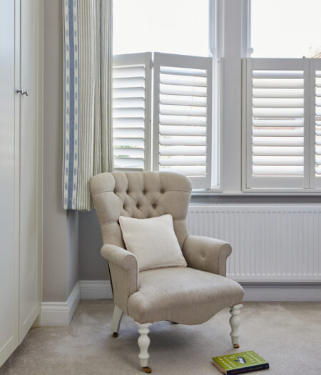 beige armchair and window with hardwood cafe style shutters