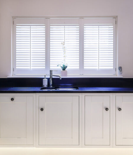 detail of a kitchen cabinet in front of a window with white abs shutters