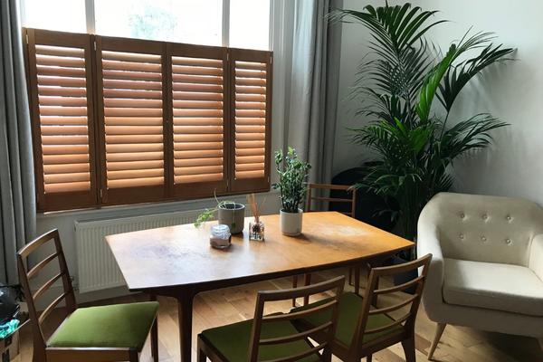 cafe style shutters in hardwood allow to match the colour of the wooden furniture in the room