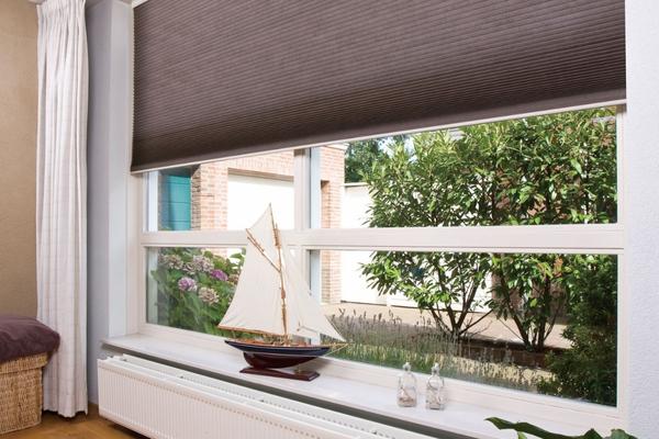 large window with a dark honeycomb blind with a cord loop mechanism