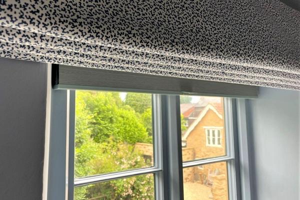 detail of a window with honeycomb blind mounted behind a roman blind