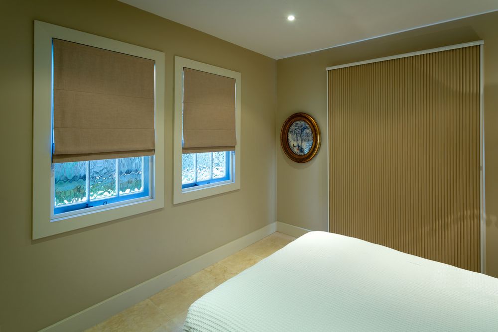 bedroom with vertical honeycomb blind  and two smaller windows with roller blinds